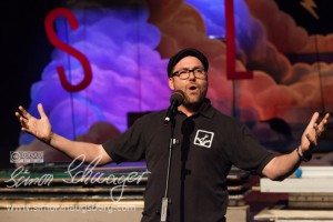 Horst Thieme ist der Moderator des Augsburger Poetry Slams. Er ist ein Mann mit Brille, Bart und Schiebermütze.